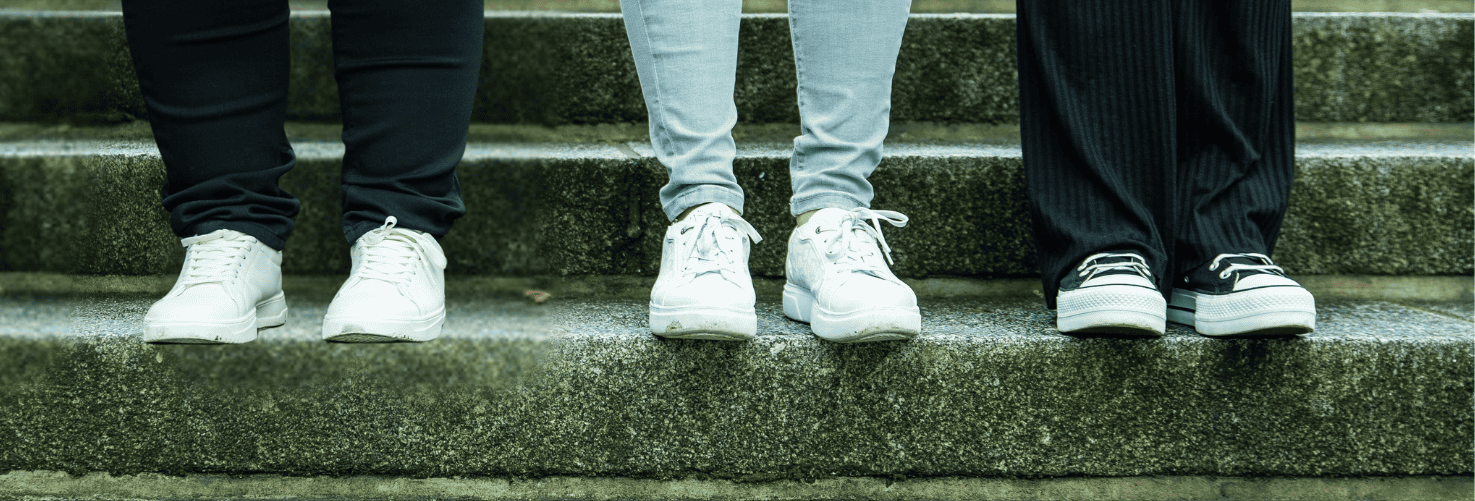 Die Schuhe der drei Inhaberinnen auf einer Treppenstufe